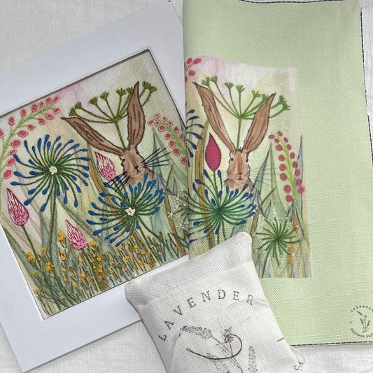 Two embroidered pieces with rabbit and floral designs on a white fabric background.