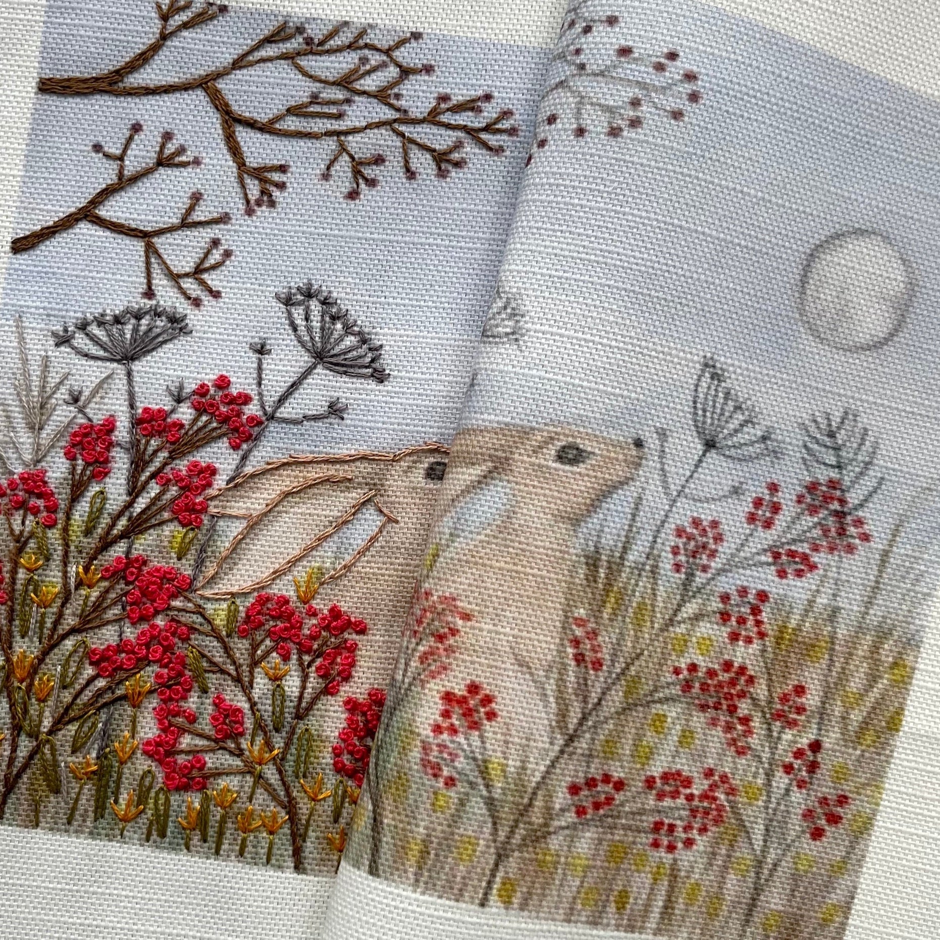 Two embroidered fabric swatches with floral and moon designs on a textured surface.