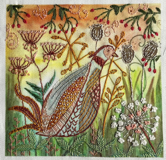 Embroidered design of a bird among flowers and plants on fabric.