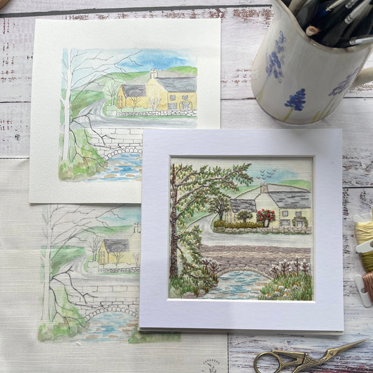 Framed artwork of a landscape scene on a wooden surface with stationery items.