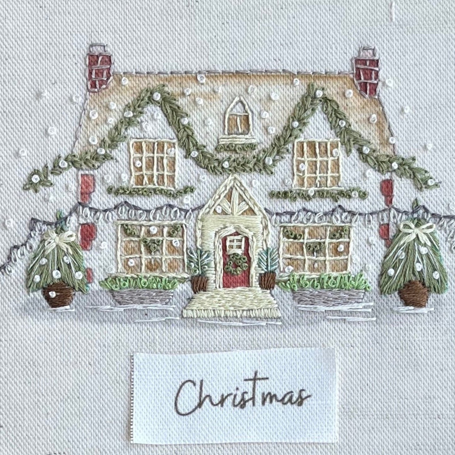 Decorative Christmas scene with a house, trees, and 'Christmas' card on a textured background