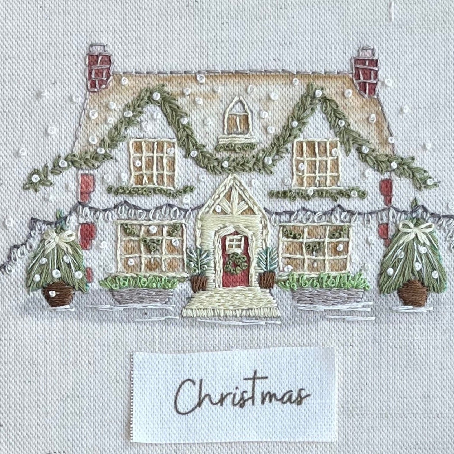 Decorative Christmas scene with a house, trees, and 'Christmas' card on a textured background