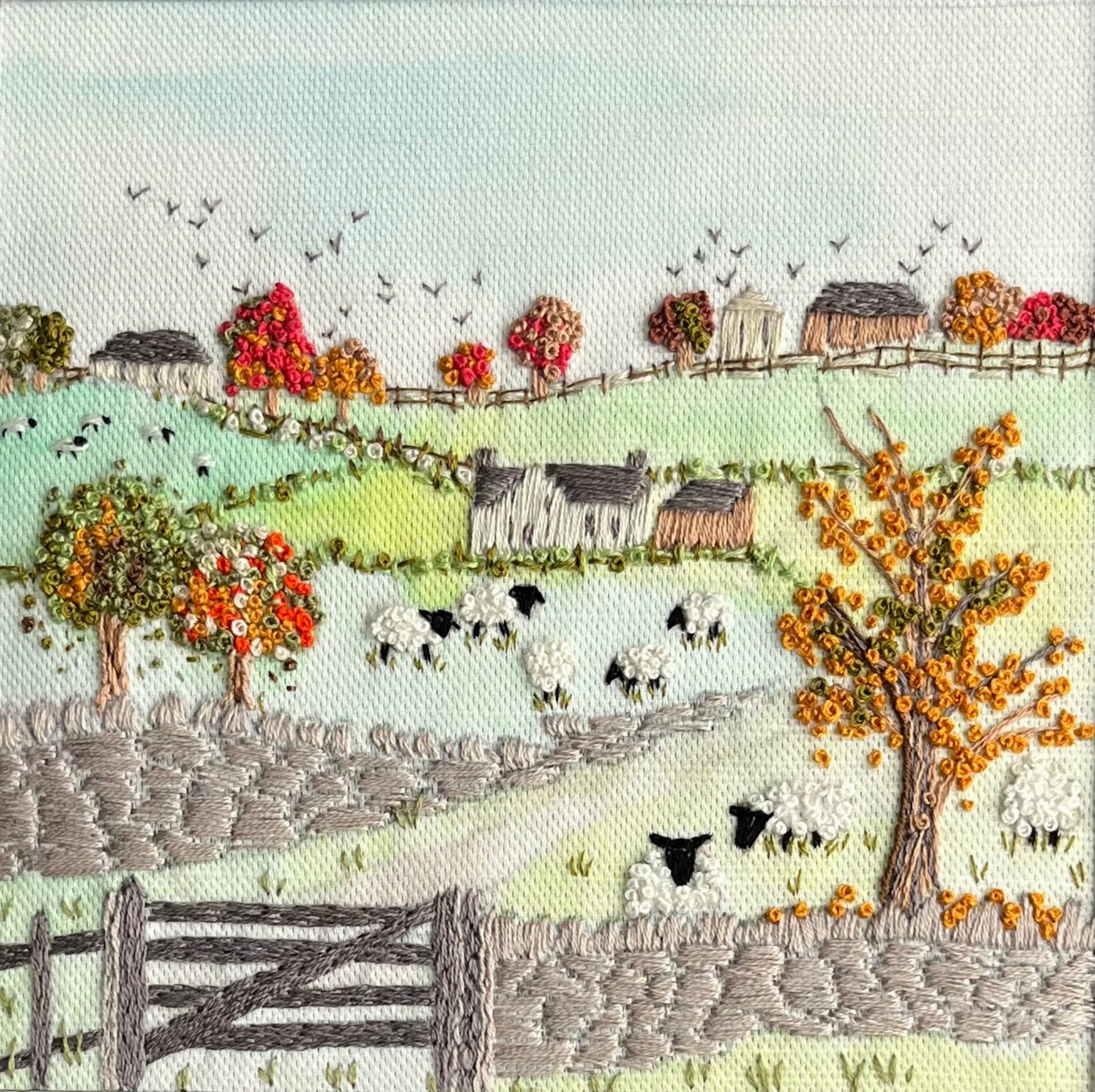 Embroidered landscape with sheep, trees, and a fence.